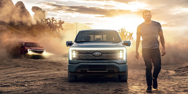 Ford f-250 front view with man walking towards camera. Dust in the background