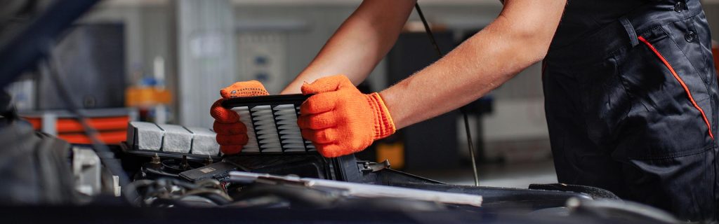 Mechanic installing a new engine air filter into a vehicle.