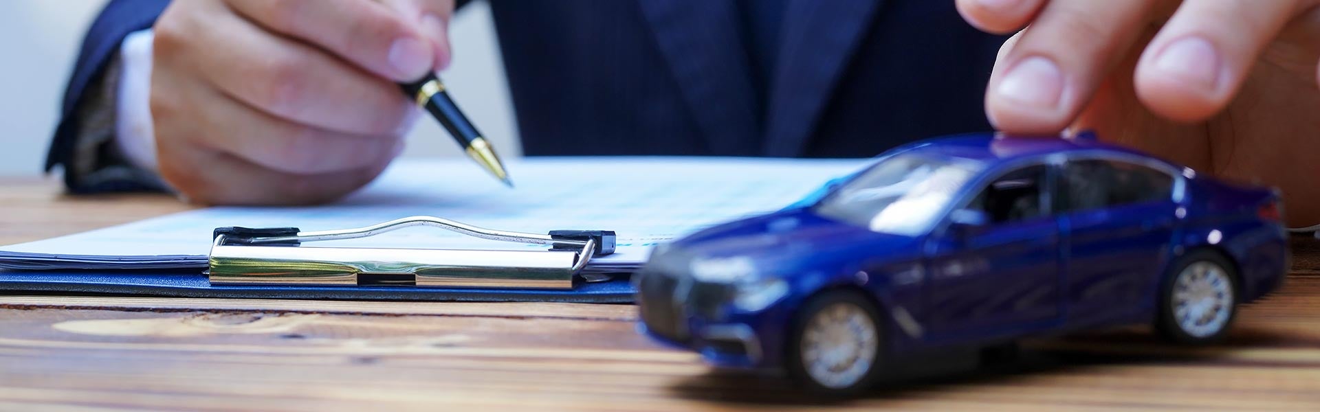 Person signing paper next to a blue toy car
